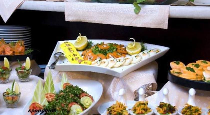 โรงแรมมากาเรม อุมม์ อัลกุรา Mecca ภายนอก รูปภาพ The photo shows a beautifully arranged platter of food. On a triangular white plate, there are neatly arranged slices of smoked salmon, garnished with lemon slices and some herbs. Surrounding the salmon are other items that appear to be slices of a l