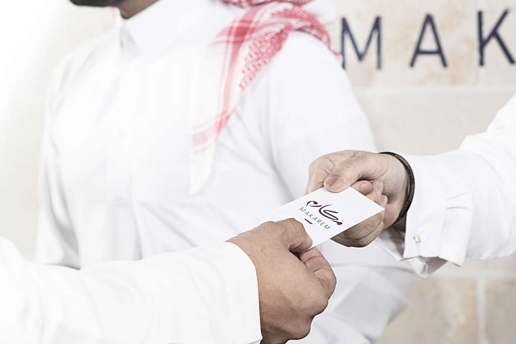 โรงแรมมากาเรม อุมม์ อัลกุรา Mecca สิ่งอำนวยความสะดวก รูปภาพ The photo depicts two individuals engaged in a handover, where one person is passing a business card to another. The person receiving the card appears to be wearing a traditional garment. The background seems to suggest a professional or formal setti
