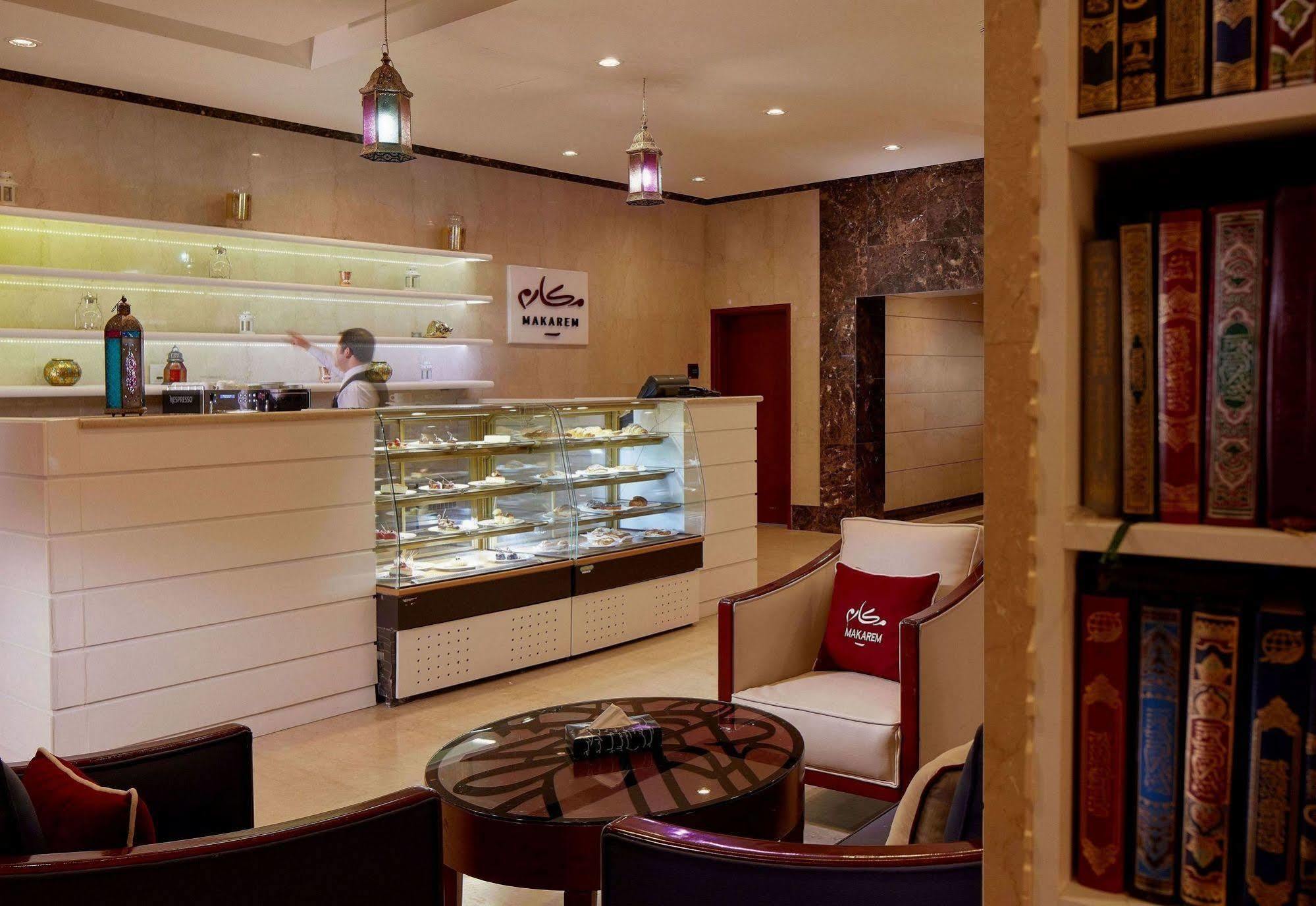โรงแรมมากาเรม อุมม์ อัลกุรา Mecca ภายนอก รูปภาพ The photo shows a stylish interior of a reception area, likely from a boutique hotel or a luxurious establishment. The front desk is modern and well-lit, with a glass display case showcasing various items. There are elegant seating arrangements, incl